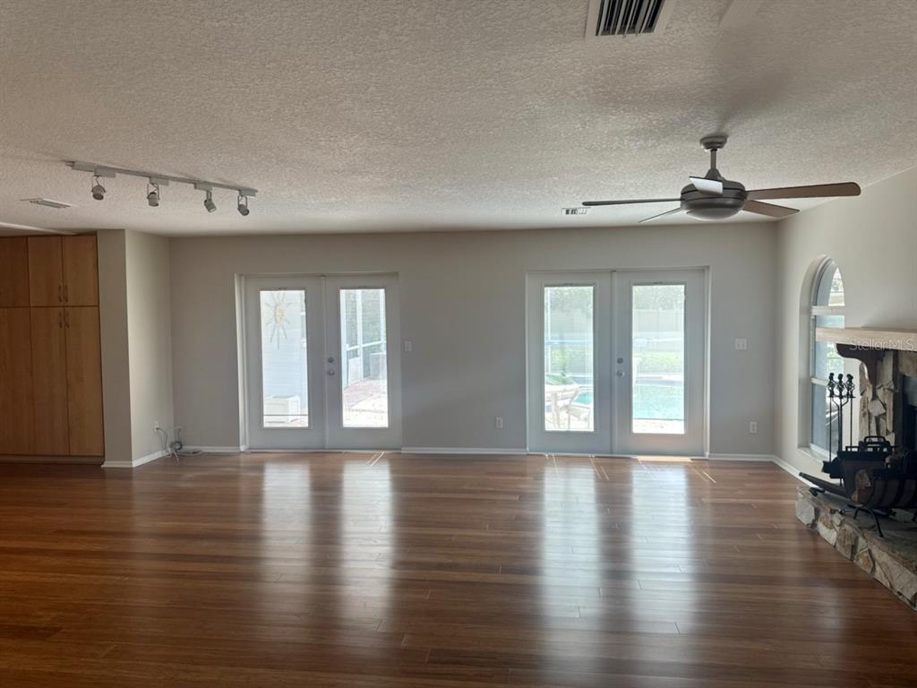 A spacious living room features hardwood floors, two sets of French doors, and a stone fireplace — 13824 83RD PLACE, SEMINOLE, FL