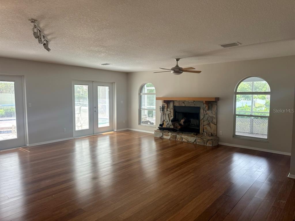 A spacious living room features hardwood floors, a stone fireplace, and glass doors to outside — 13824 83RD PLACE, SEMINOLE, FL