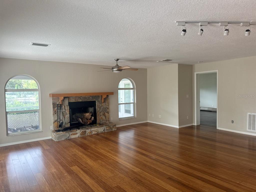 A living room features a stone fireplace, hardwood floors, arched windows, and track lighting — 13824 83RD PLACE, SEMINOLE, FL