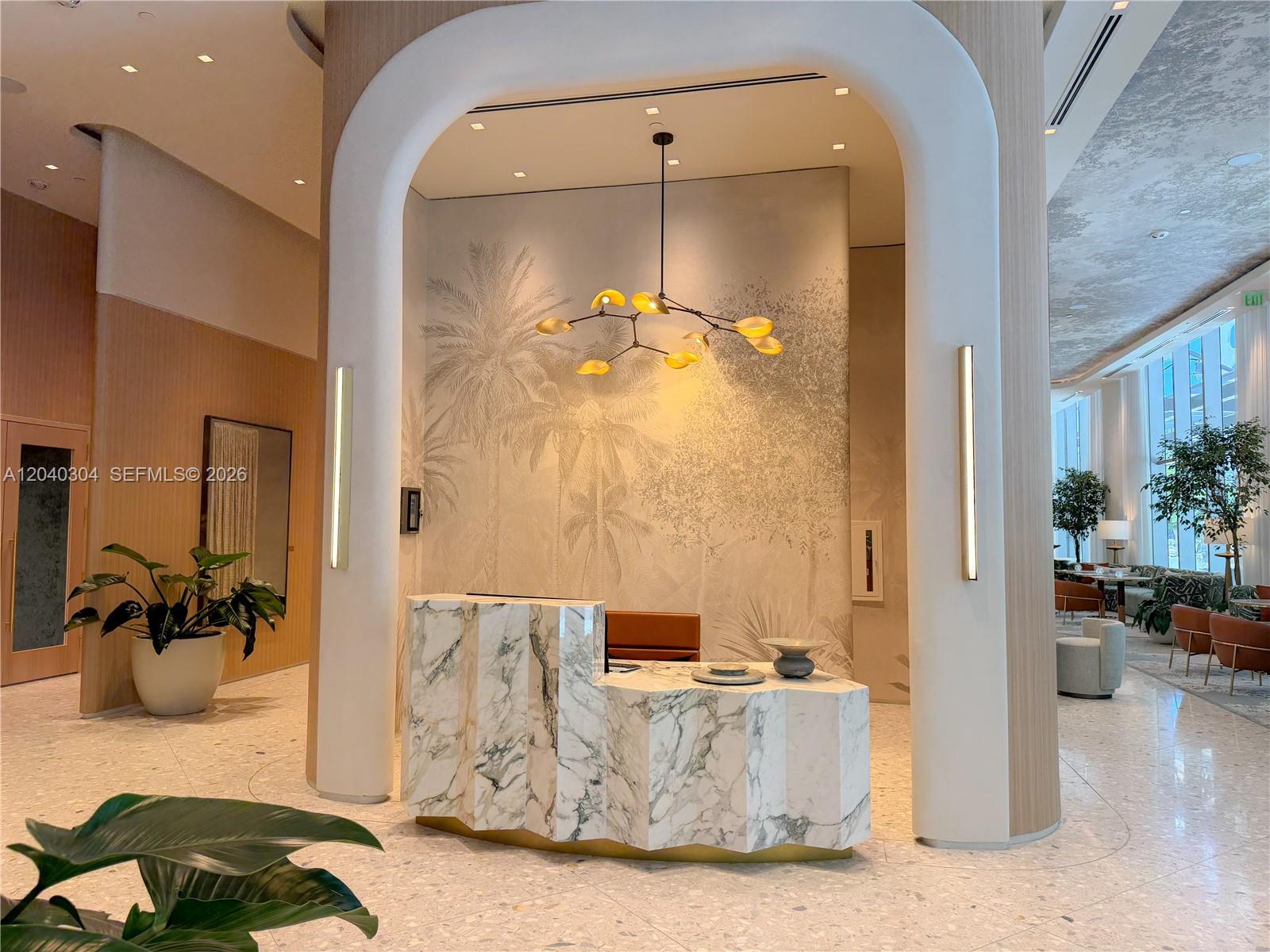 A modern lobby features a marble reception desk under an arched alcove with palm wallpaper — 77 SE 5 # 4015, Miami FL 33131, MIAMI, FL