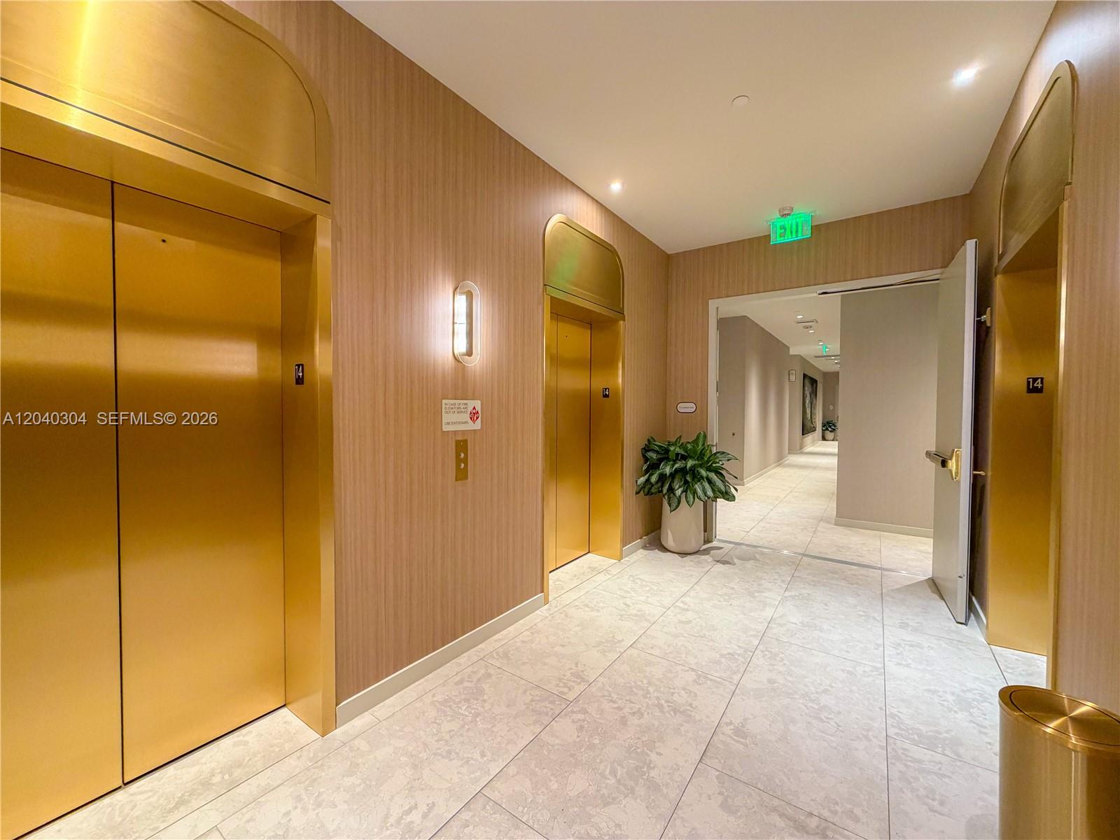 An elevator lobby features gold-toned doors, wood-paneled walls, and light-colored tile flooring — 77 SE 5 # 4015, Miami FL 33131, MIAMI, FL