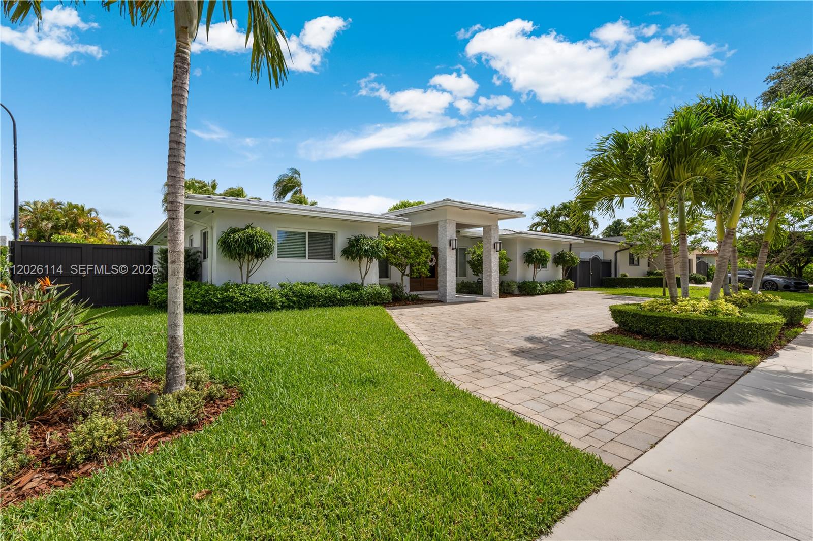 A white single-story house features a paved driveway, palm trees, and a manicured lawn — 9641 SW 66th St, Miami FL 33173, MIAMI, FL