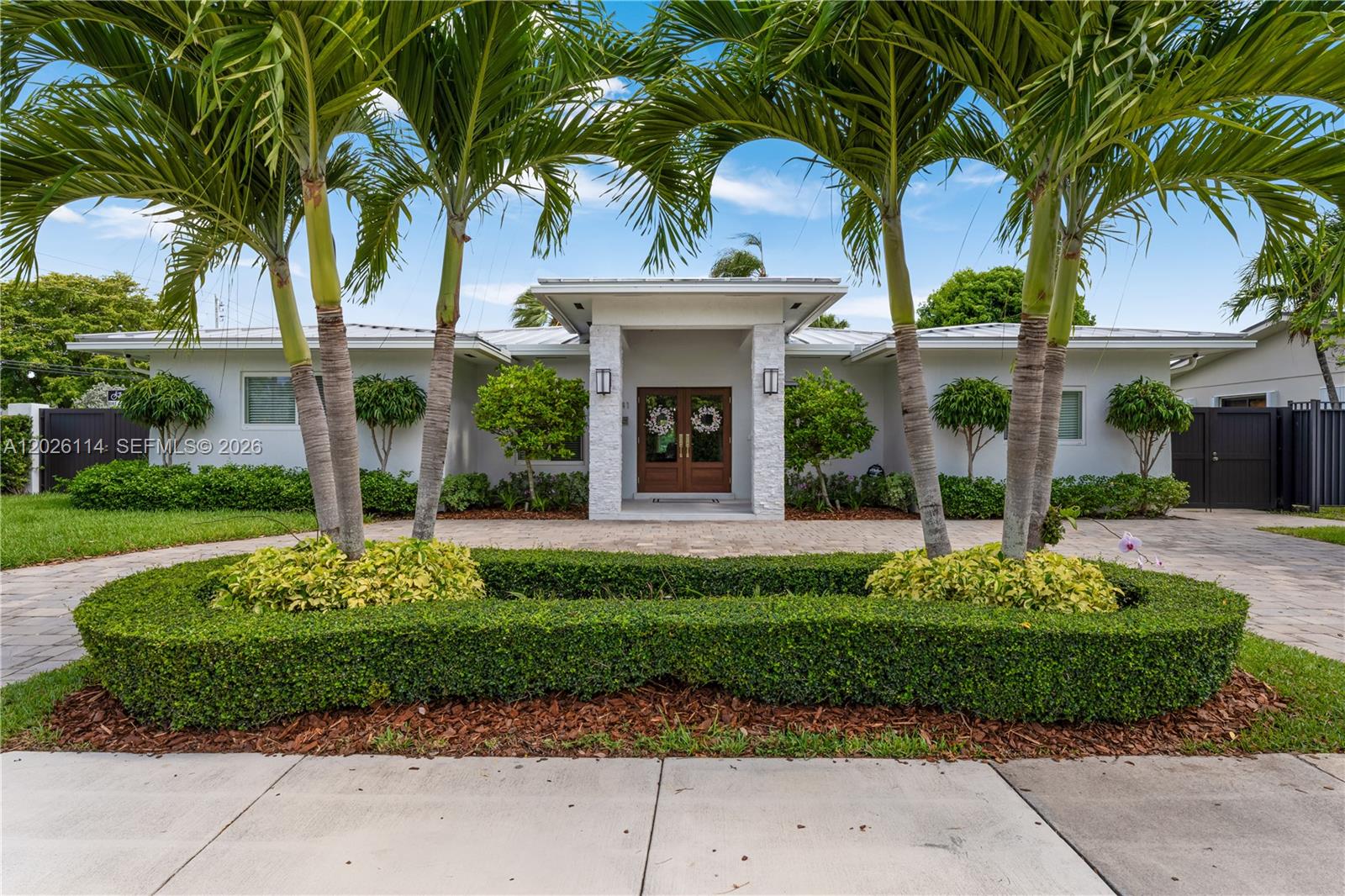 A single-story house features a paved driveway, palm trees, and a central stone-accented entryway — 9641 SW 66th St, Miami FL 33173, MIAMI, FL