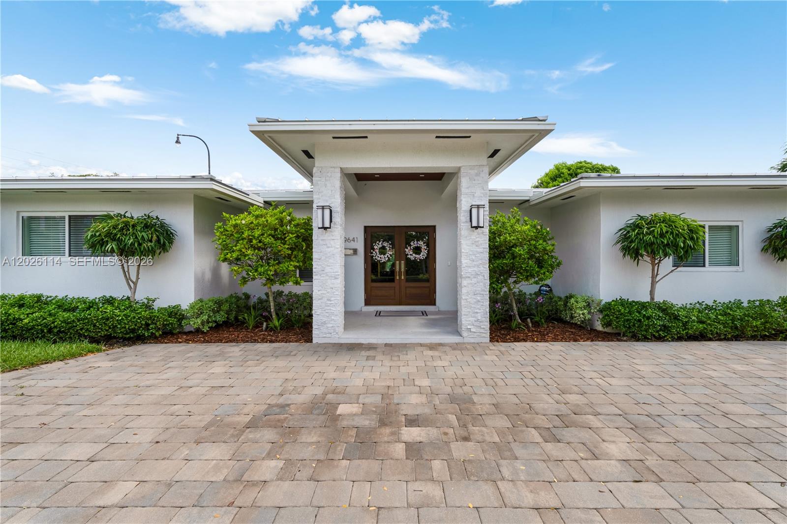 A single-story house features a stone-accented entryway with double doors and a paved driveway — 9641 SW 66th St, Miami FL 33173, MIAMI, FL