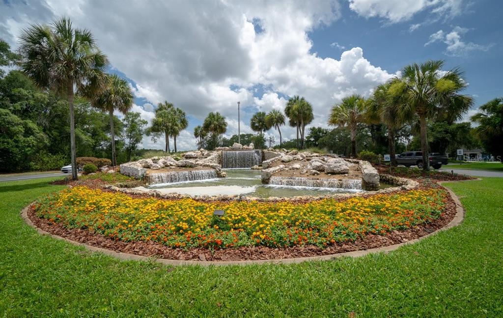 A circular garden with a stone waterfall feature surrounded by palm trees and green grass — SW 165TH PLACE, OCALA, FL
