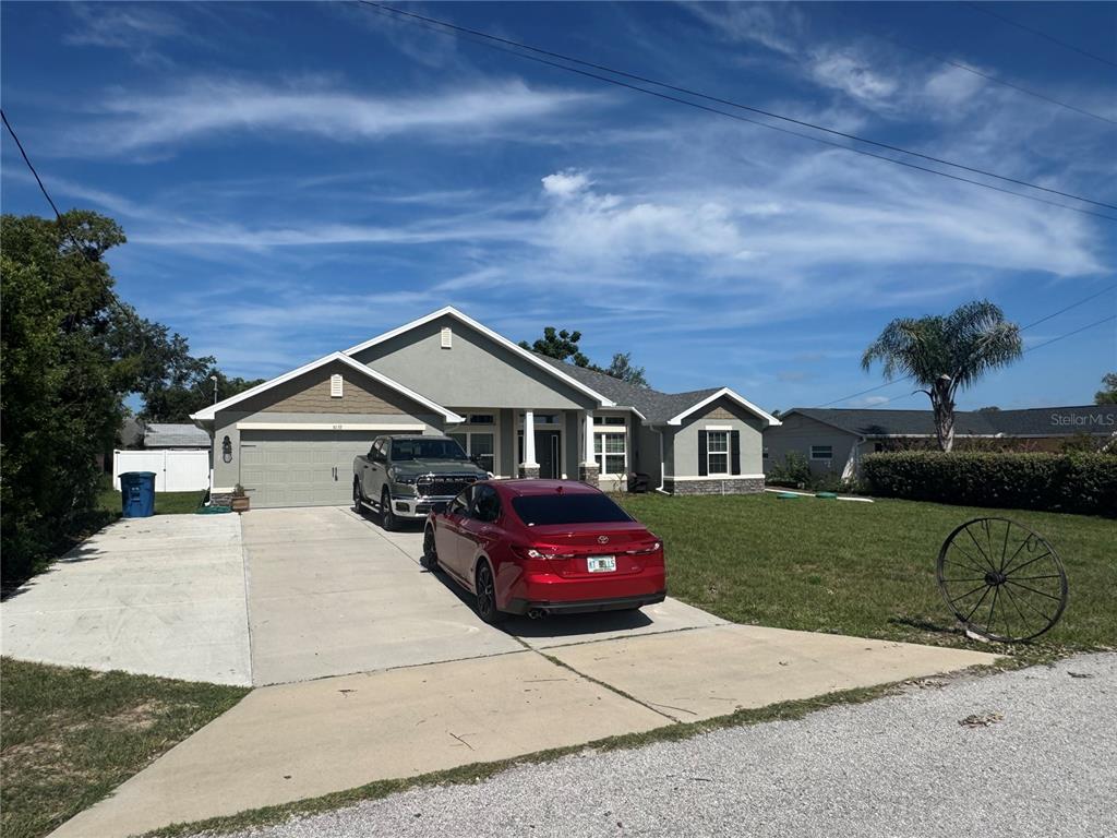 A single-story house with a two-car garage, a concrete driveway, and two parked vehicles — 5139 JENSON AVENUE, SPRING HILL, FL
