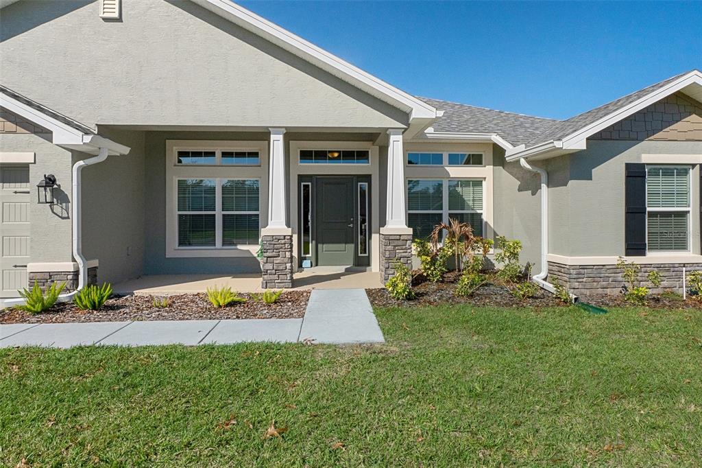 The exterior of a single-story house features a covered porch, stone accents, and green shutters — 5139 JENSON AVENUE, SPRING HILL, FL