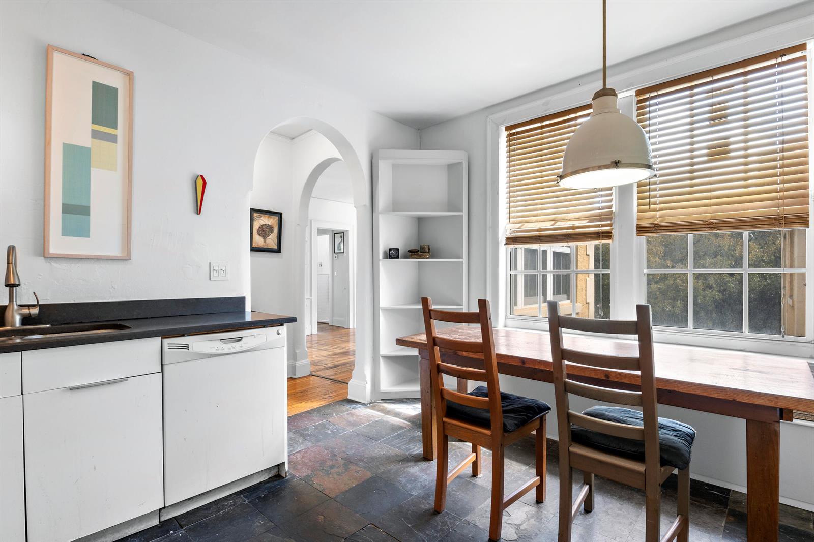 A kitchen with white cabinets, a wooden dining table, and an arched doorway — 3224 Biscayne Boulevard # A3, Miami FL 33137, MIAMI, FL
