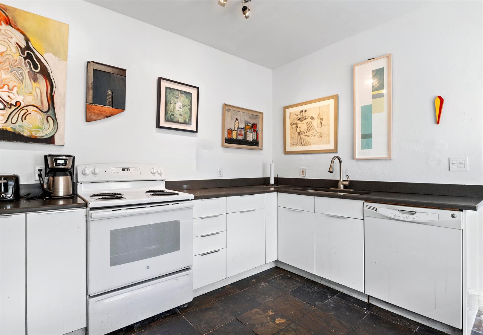 A kitchen with white cabinets, a white stove, a dishwasher, and dark stone flooring — 3224 Biscayne Boulevard # A3, Miami FL 33137, MIAMI, FL