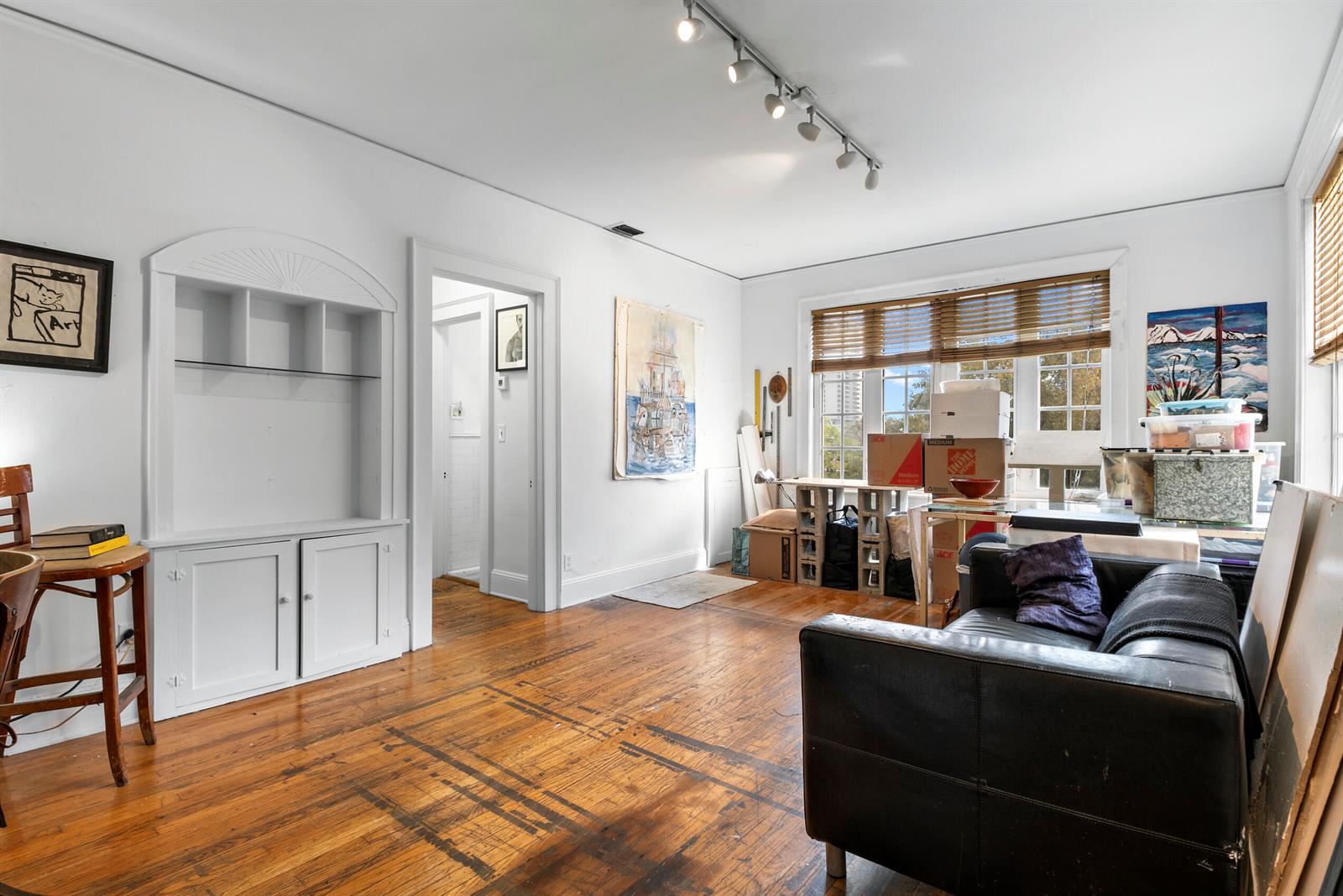 A living room with hardwood floors, a built-in cabinet, track lighting, and a black sofa — 3224 Biscayne Boulevard # A3, Miami FL 33137, MIAMI, FL
