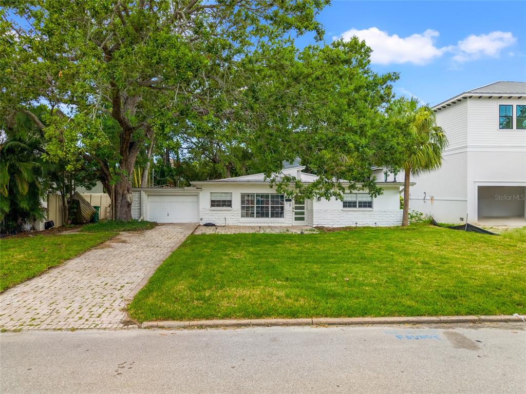 A single-story white house with a brick driveway and a large tree in the yard — 614 ONTARIO AVENUE, TAMPA, FL