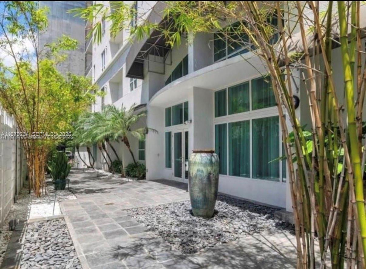A paved walkway leads to a building entrance featuring a large decorative ceramic urn — 234 NE 3rd St # 608, Miami FL 33132, MIAMI, FL