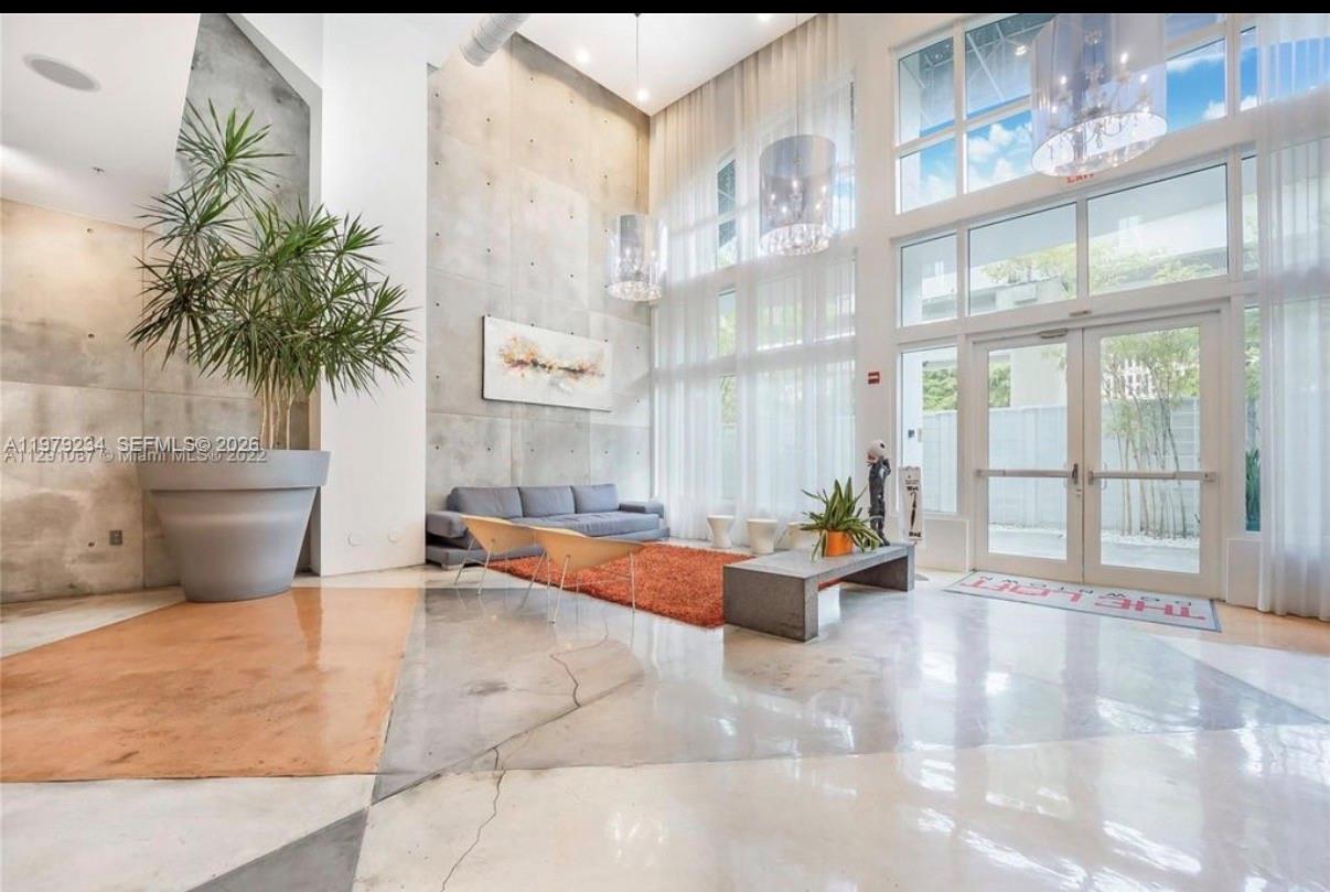 A modern lobby features a high ceiling, concrete wall, large windows, and polished concrete floors — 234 NE 3rd St # 608, Miami FL 33132, MIAMI, FL
