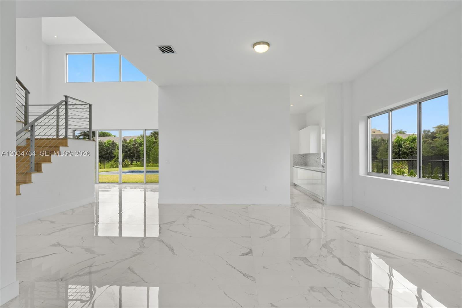 A bright, open-concept living area features white marble floors, a staircase, and a kitchen view — 16710 N Botaniko Dr N, Weston FL 33326, WESTON, FL