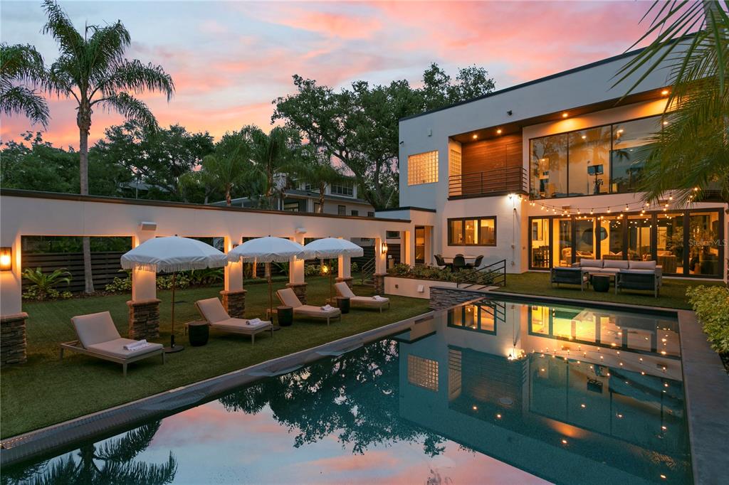 A modern two-story house features a swimming pool, lounge chairs, and string lights at sunset — 2515 W SHELL POINT ROAD, TAMPA, FL