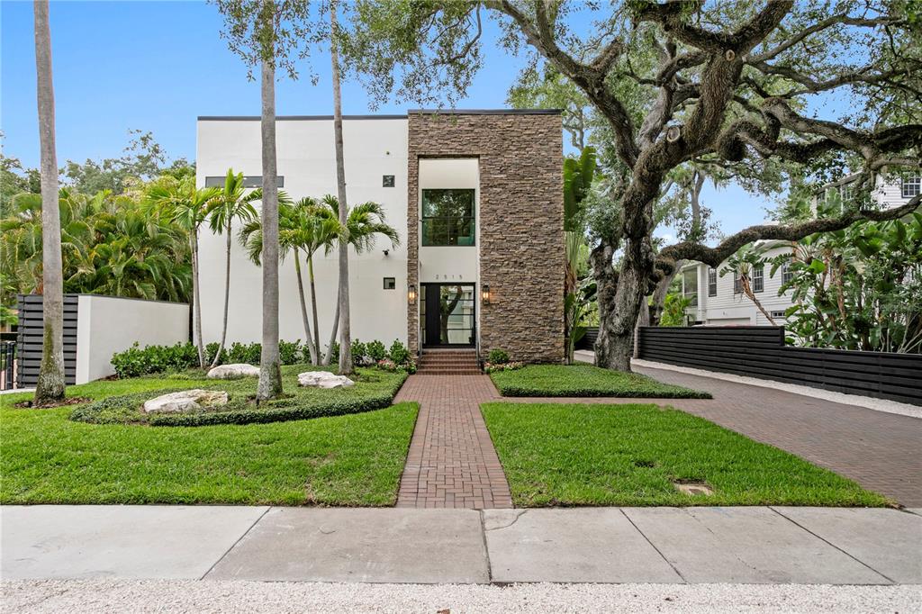 A modern two-story house features a stone facade, white walls, and a brick walkway — 2515 W SHELL POINT ROAD, TAMPA, FL