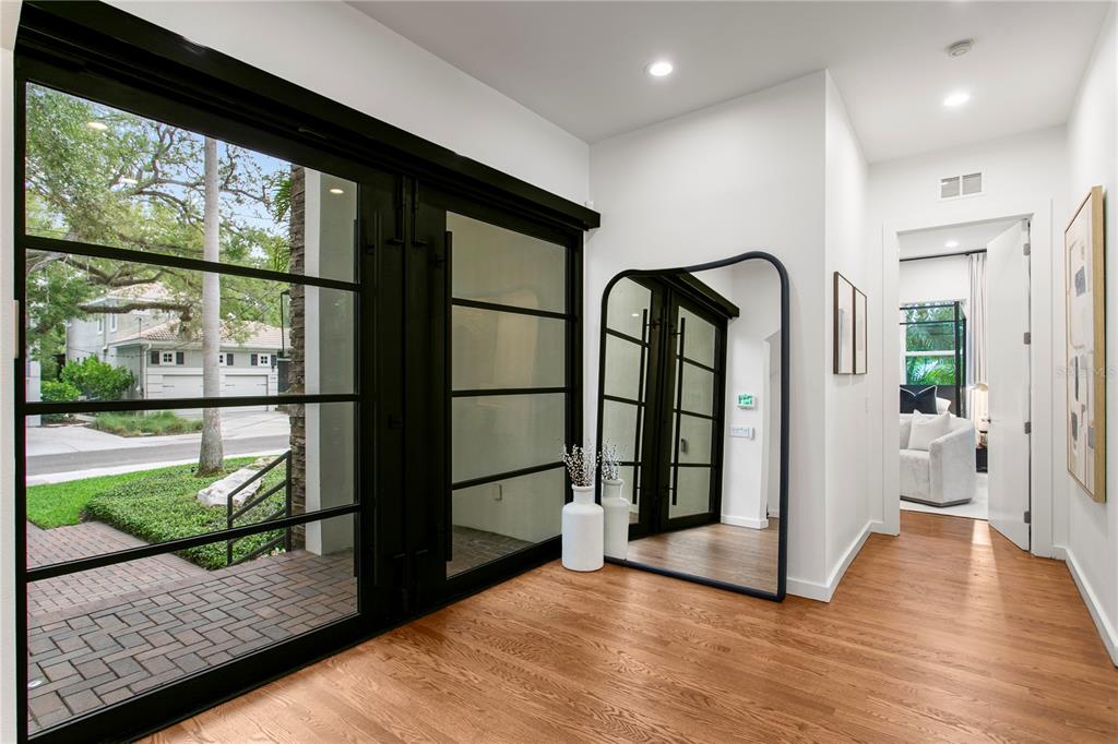 An entryway features hardwood floors, a large arched floor mirror, and black-framed glass doors — 2515 W SHELL POINT ROAD, TAMPA, FL