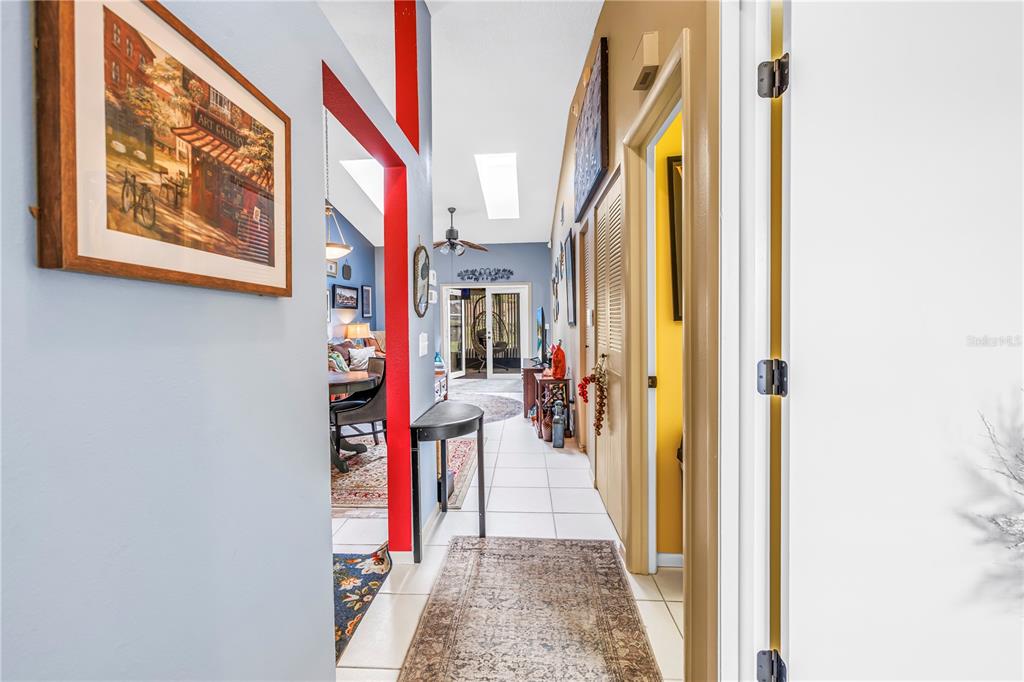 A hallway with tiled floors leads to a living area with vaulted ceilings and skylights — 2932 64TH STREET W UNIT 2932, BRADENTON, FL