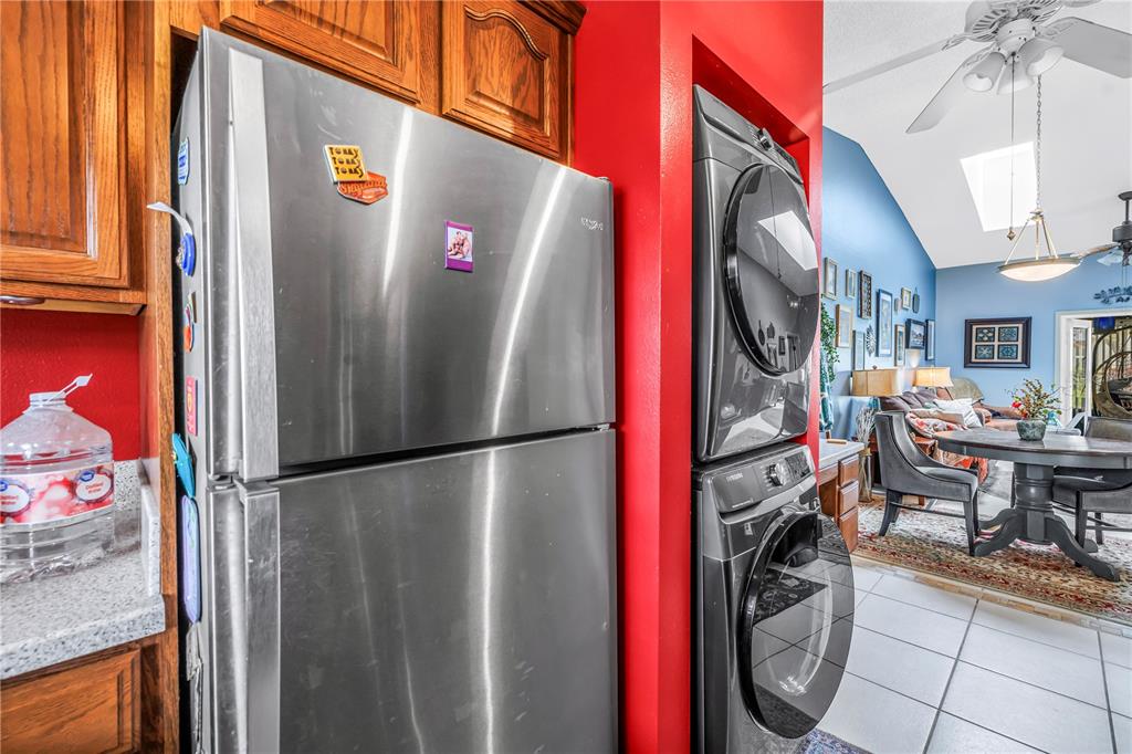 A stainless steel refrigerator sits next to a stacked washer and dryer in a kitchen — 2932 64TH STREET W UNIT 2932, BRADENTON, FL