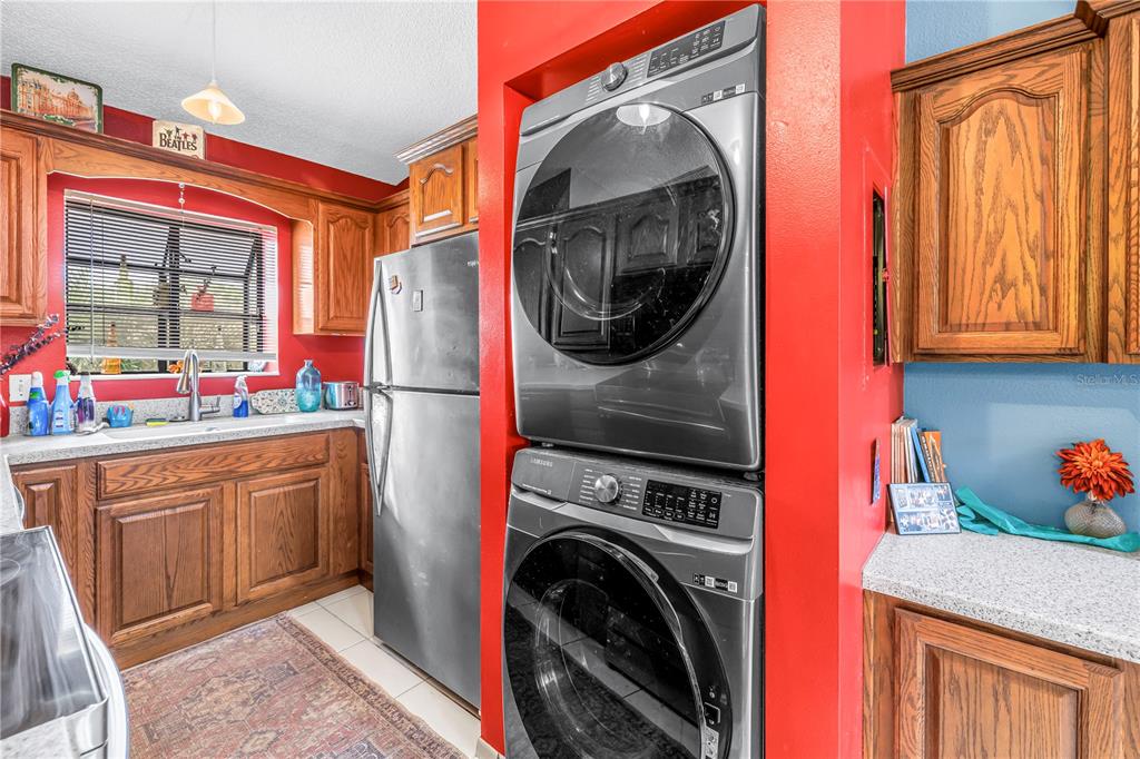 A kitchen with wood cabinets, a stainless steel refrigerator, and a stacked washer and dryer — 2932 64TH STREET W UNIT 2932, BRADENTON, FL