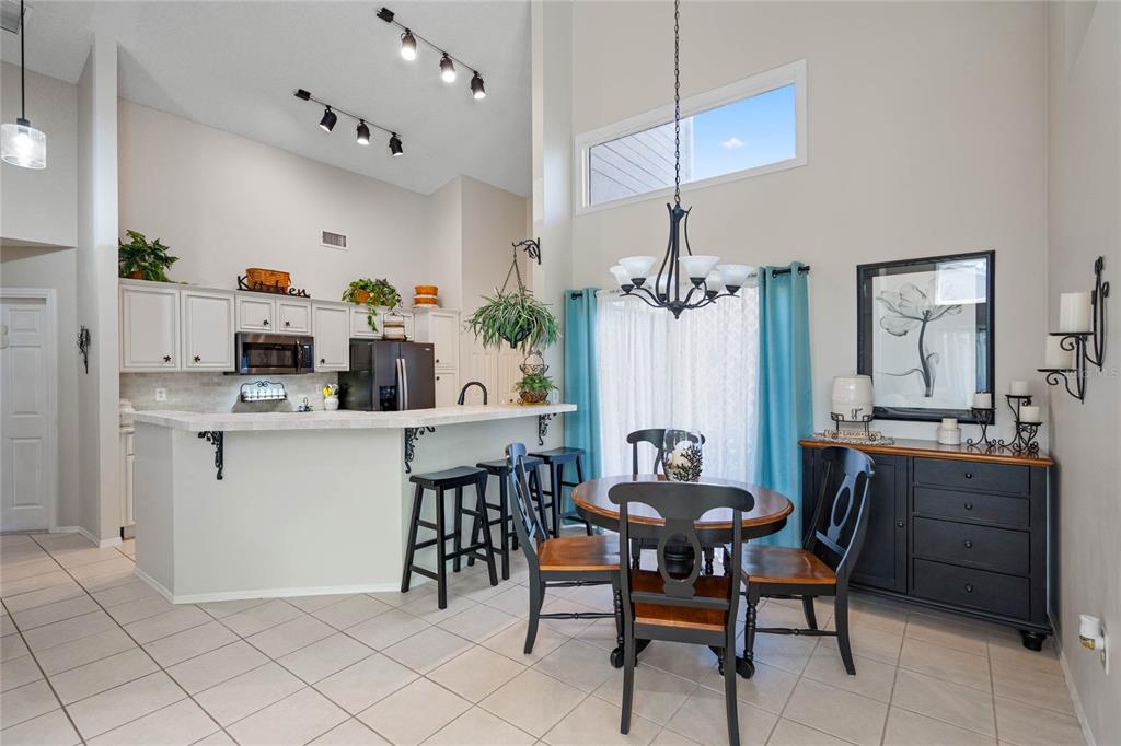 A kitchen with a breakfast bar and an adjacent dining area with tile flooring — 7815 GENEVA LANE, SARASOTA, FL