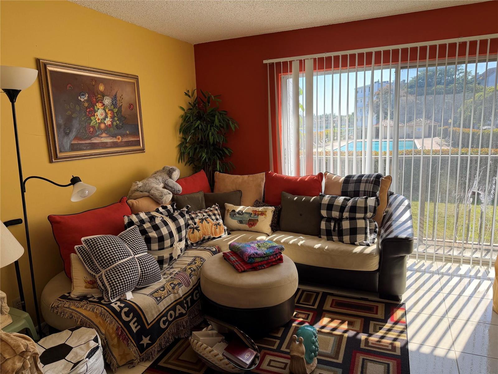 A living room features a sectional sofa, a patterned area rug, and a sliding glass door — 8620 N Sherman Circle # 204, Miramar FL 33025, MIRAMAR, FL