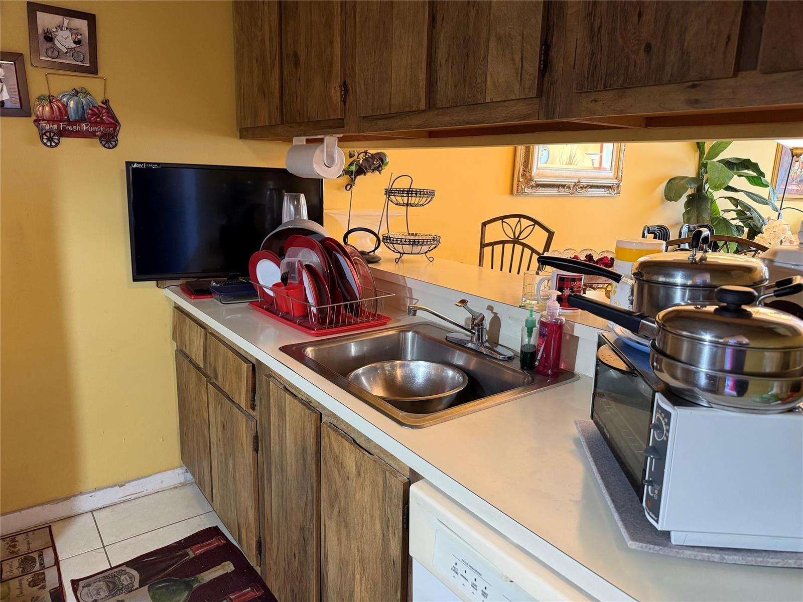 A kitchen with wood cabinets, white appliances, a tile floor, and a pass-through window — 8620 N Sherman Circle # 204, Miramar FL 33025, MIRAMAR, FL