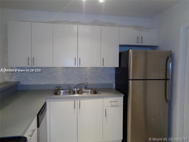 A kitchen features white cabinets, a stainless steel refrigerator, and a gray countertop — 15205 NE 6th Ave # D212, Miami FL 33162, MIAMI, FL