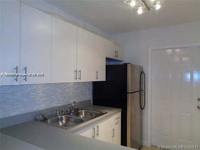 A kitchen features white cabinets, a stainless steel sink, and a black refrigerator — 15205 NE 6th Ave # D212, Miami FL 33162, MIAMI, FL