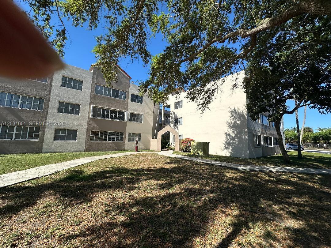A multi-story apartment building with beige stucco walls and a sidewalk leading to the entrance — 6175 NW 186th St # 110, Hialeah FL 33015, HIALEAH, FL