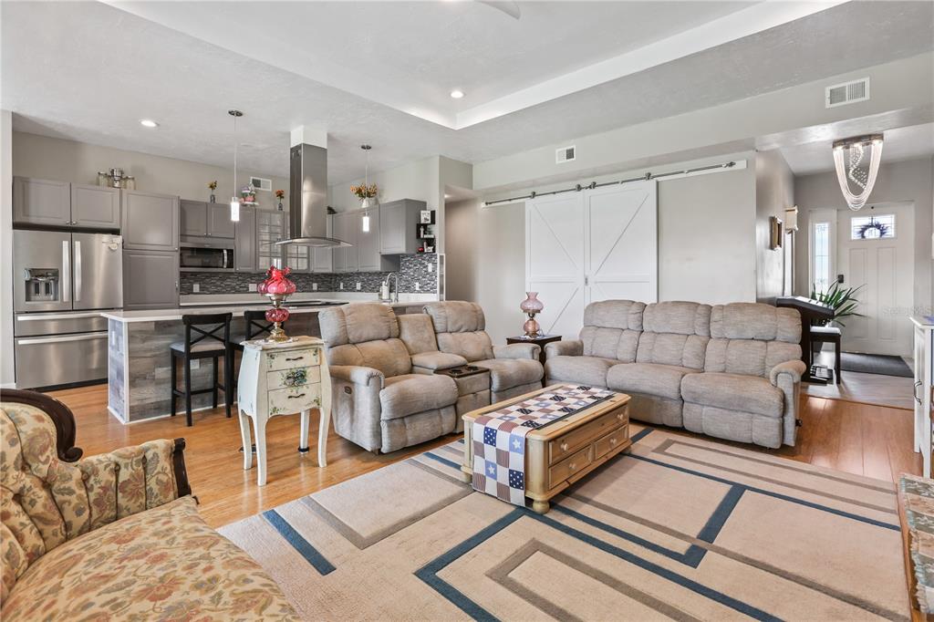 An open-concept living room and kitchen featuring gray cabinetry, stainless appliances, and neutral furniture — 306 CALENDAR STREET, PORT CHARLOTTE, FL