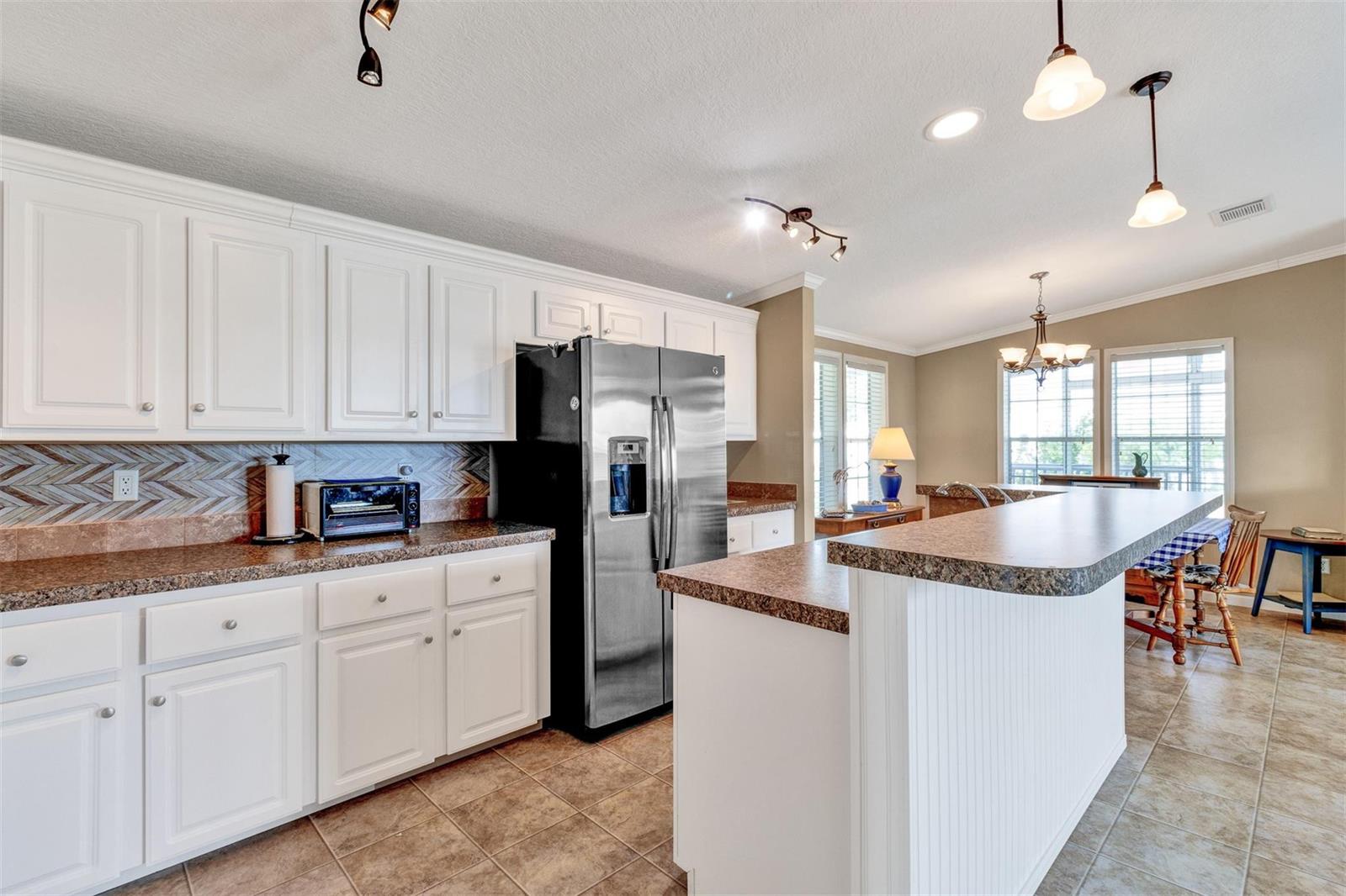 A kitchen with white cabinets, brown countertops, stainless steel appliances, and a breakfast bar — 192 N Arbor Lane, Vero Beach FL 32960, VERO BEACH, FL