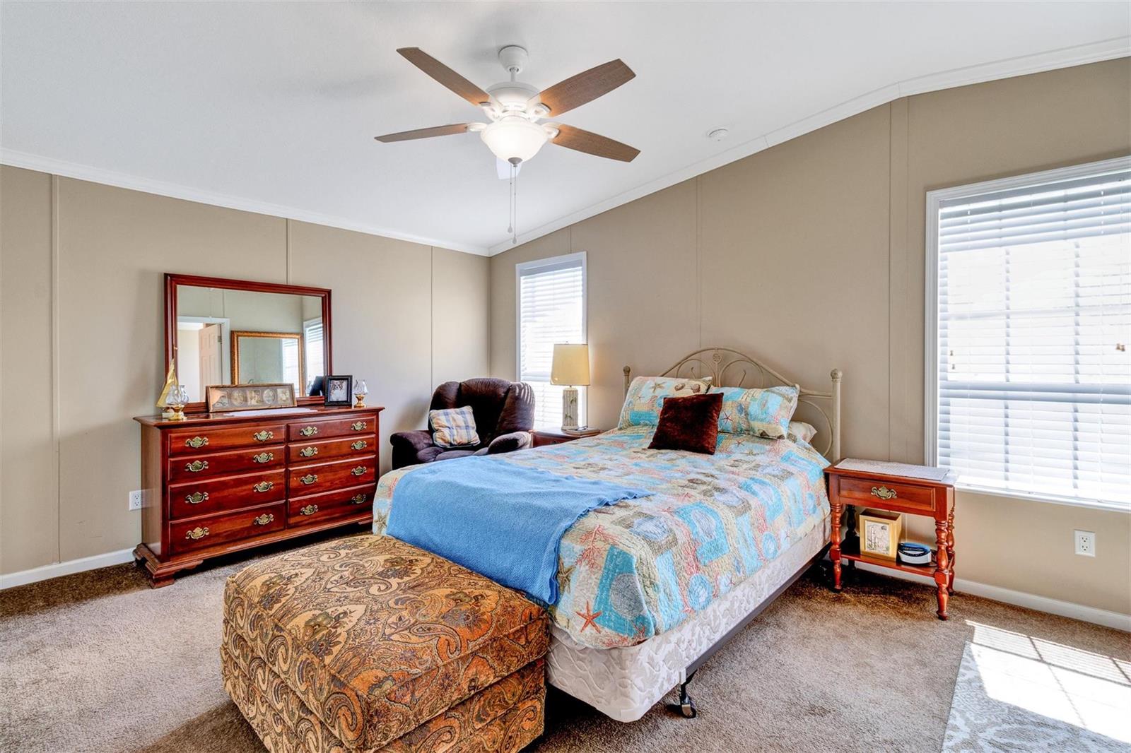 A bedroom features a bed, a wooden dresser with a mirror, and a ceiling fan — 192 N Arbor Lane, Vero Beach FL 32960, VERO BEACH, FL