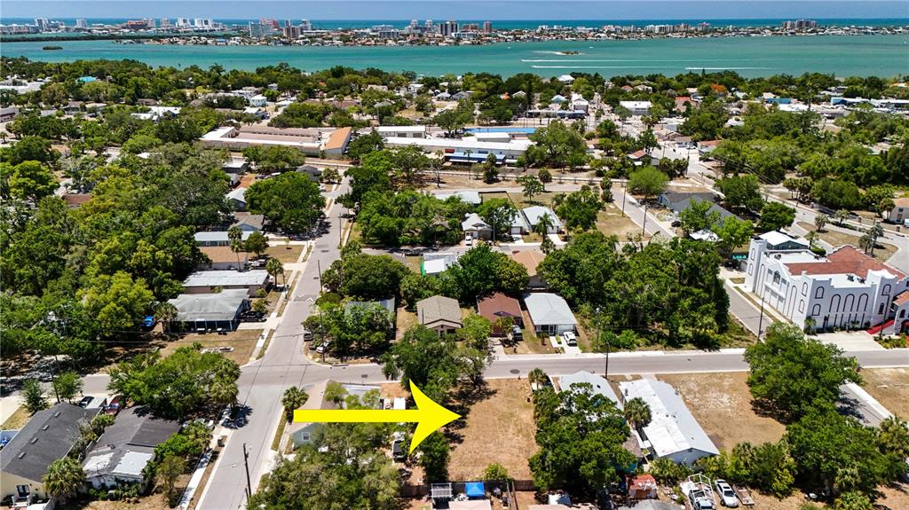 An aerial view shows a vacant residential lot marked by a yellow arrow near water — 1405 PENNSYLVANIA AVENUE, CLEARWATER, FL