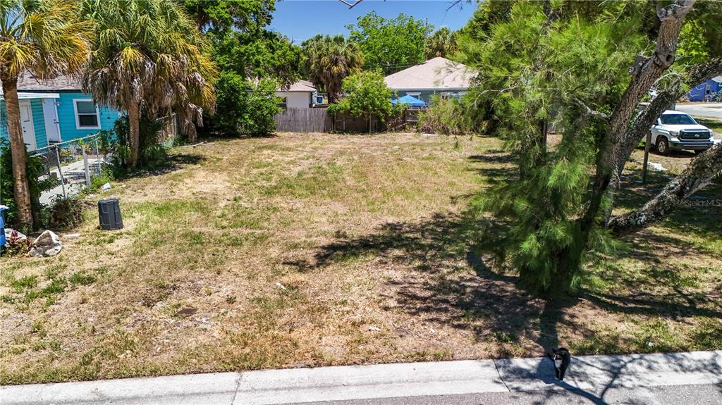 A vacant, grassy residential lot sits between a turquoise house and a large tree — 1405 PENNSYLVANIA AVENUE, CLEARWATER, FL