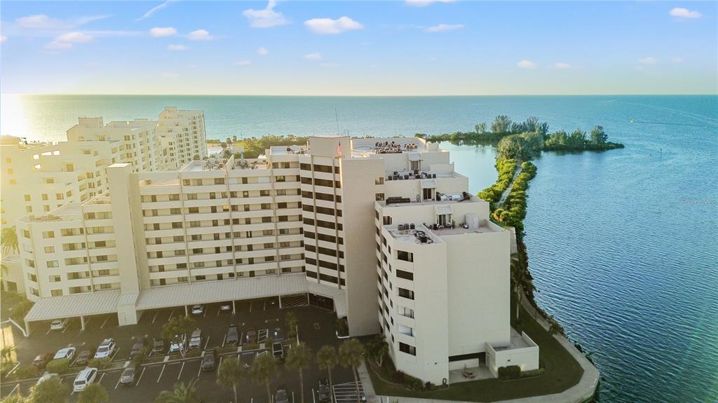 An aerial view of a multi-story apartment building situated along a waterfront with a parking lot — 6035 SEA RANCH DRIVE UNIT 415, HUDSON, FL