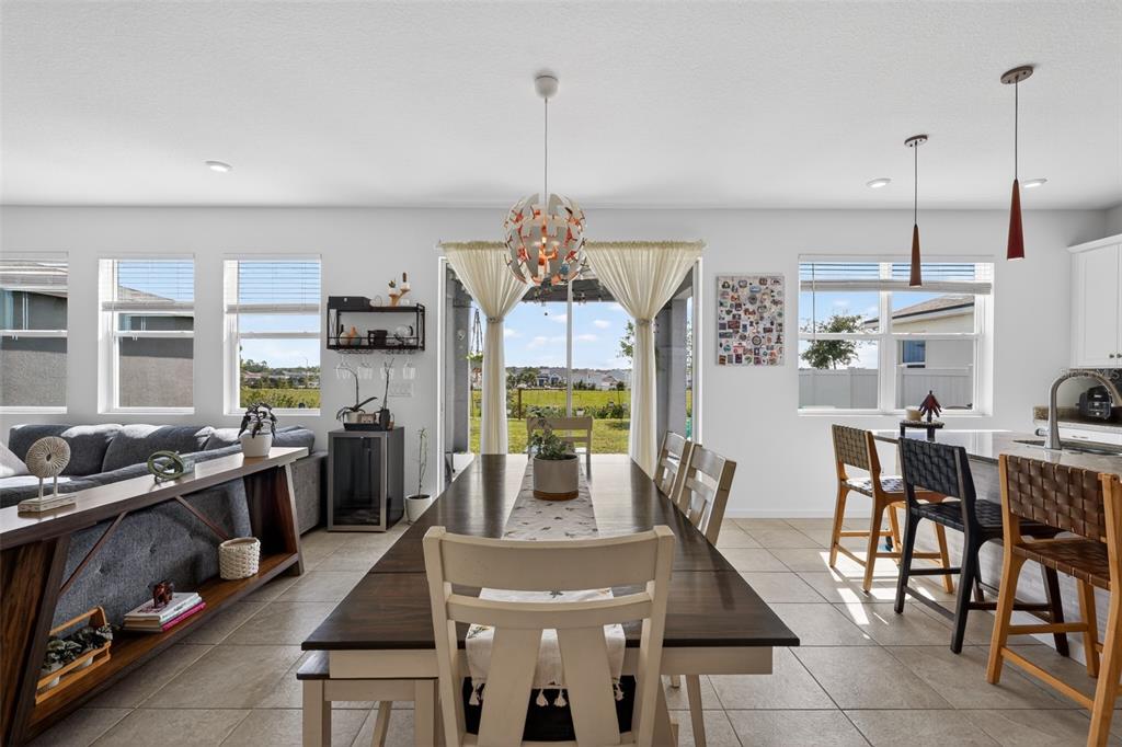 A dining area with a wooden table, pendant lighting, and an adjacent kitchen island — 1181 LAKESHORE BREEZE PLACE, KISSIMMEE, FL