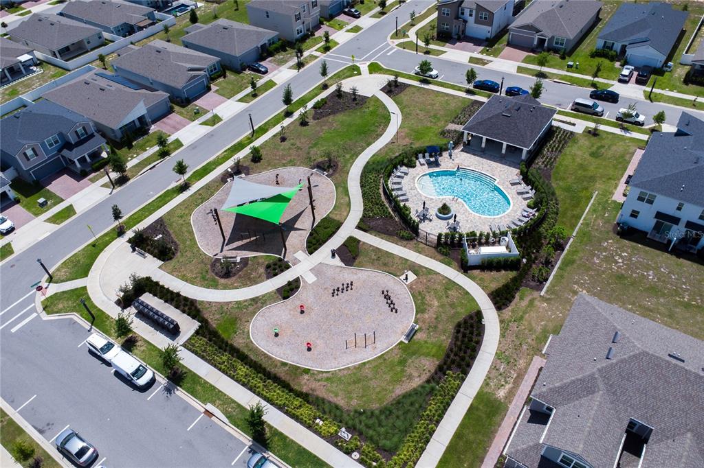 Aerial view of a neighborhood park featuring a swimming pool, playground, and paved walkways — 1181 LAKESHORE BREEZE PLACE, KISSIMMEE, FL