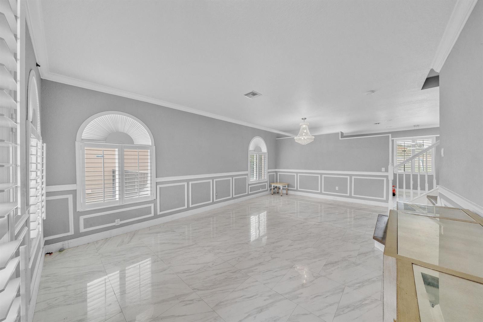 A spacious room features gray walls with white wainscoting, marble-look tile flooring, and arched windows — 149 Bellezza Terrace, Royal Palm Beach FL 33411, ROYAL PALM BEACH, FL