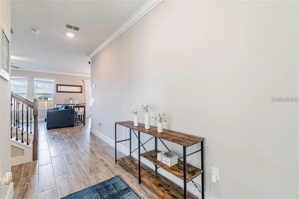 A hallway with wood-look tile flooring features a console table against a long wall — 8403 CAPSTONE RANCH DRIVE, NEW PORT RICHEY, FL