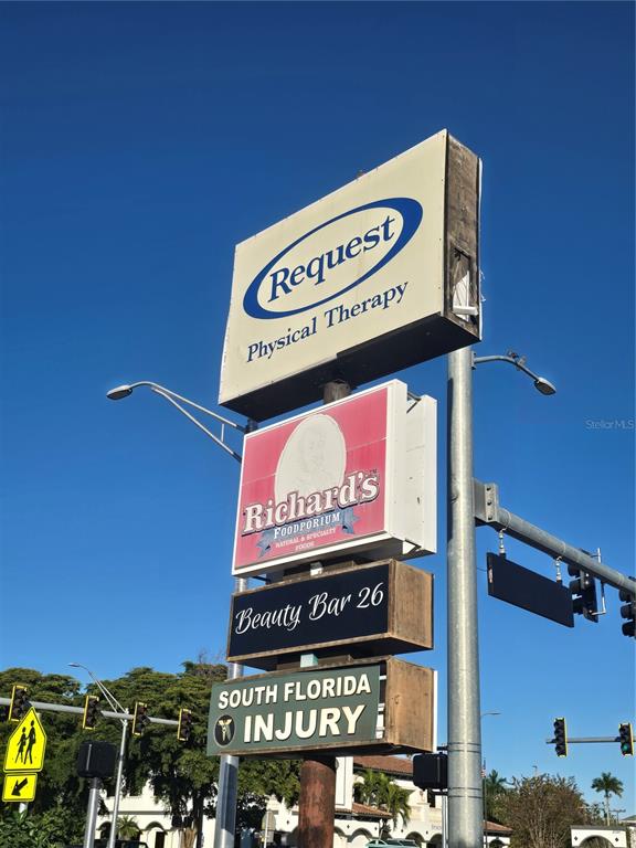 A tall, multi-tenant commercial sign stands against a clear blue sky — 2601 MANATEE AVENUE W, BRADENTON, FL