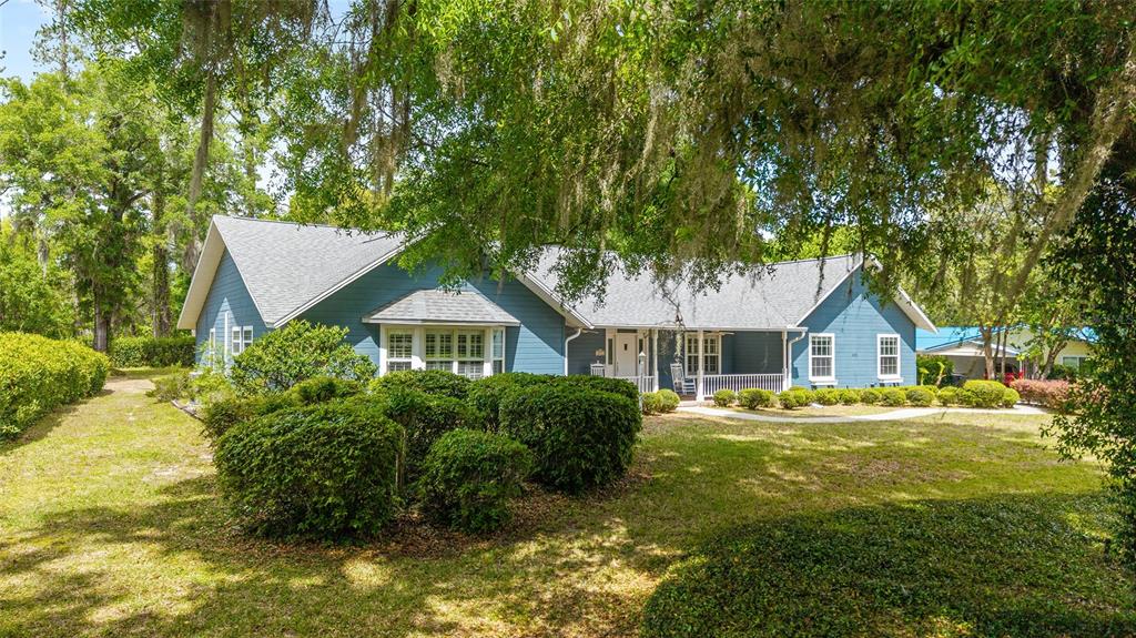 A blue, single-story house with a gray roof sits behind a large, manicured hedge — 8051 NW 43RD LANE, OCALA, FL