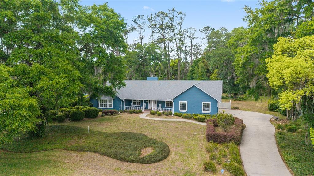 A blue, single-story ranch-style house with a gray roof sits on a wooded lot — 8051 NW 43RD LANE, OCALA, FL