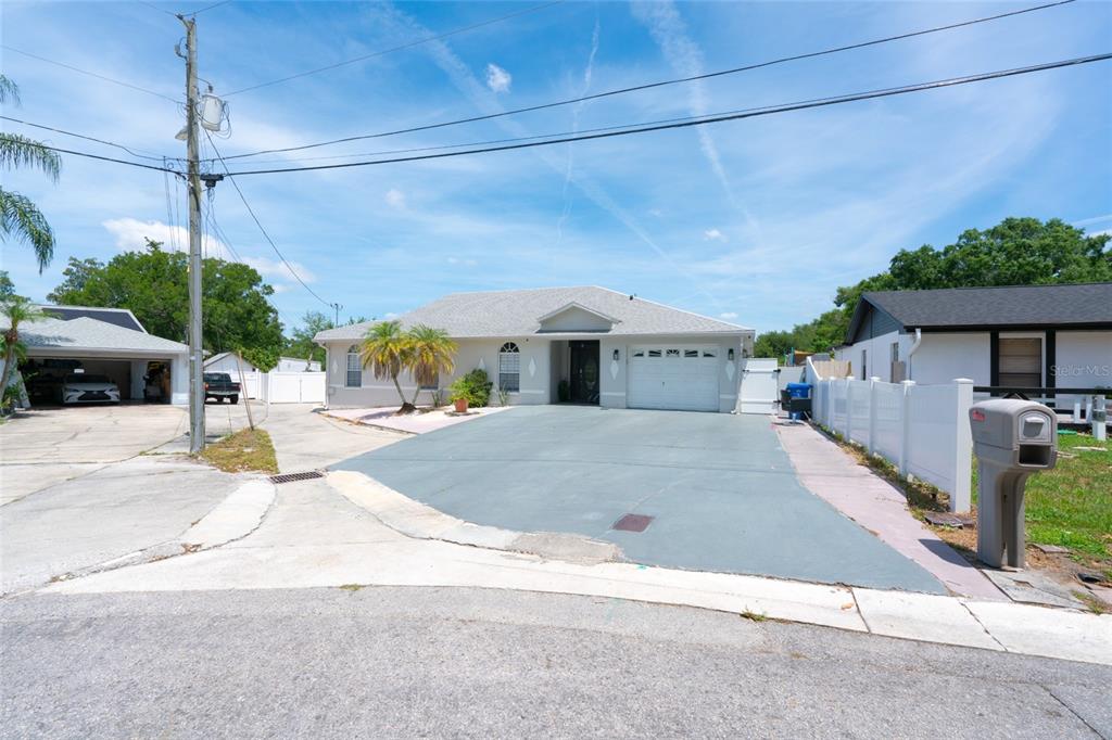 A single-story house with a gray driveway, a white garage door, and a detached carport — 3615 MARCO DRIVE, TAMPA, FL