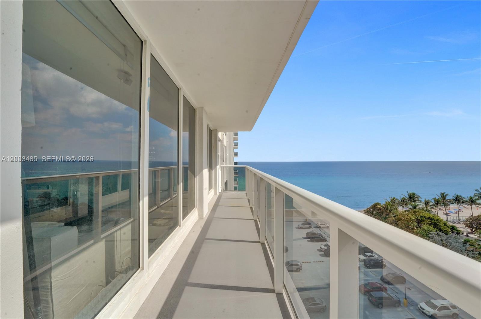 A high-rise balcony with glass railings overlooks a parking lot, beach, and the ocean — 2751 S Ocean Dr # 908S, Hollywood FL 33019, HOLLYWOOD, FL