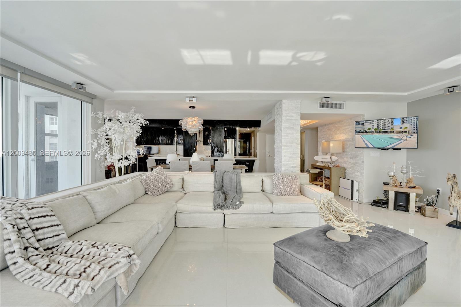 A spacious living room features a large sectional sofa, a grey ottoman, and an open kitchen — 2751 S Ocean Dr # 908S, Hollywood FL 33019, HOLLYWOOD, FL