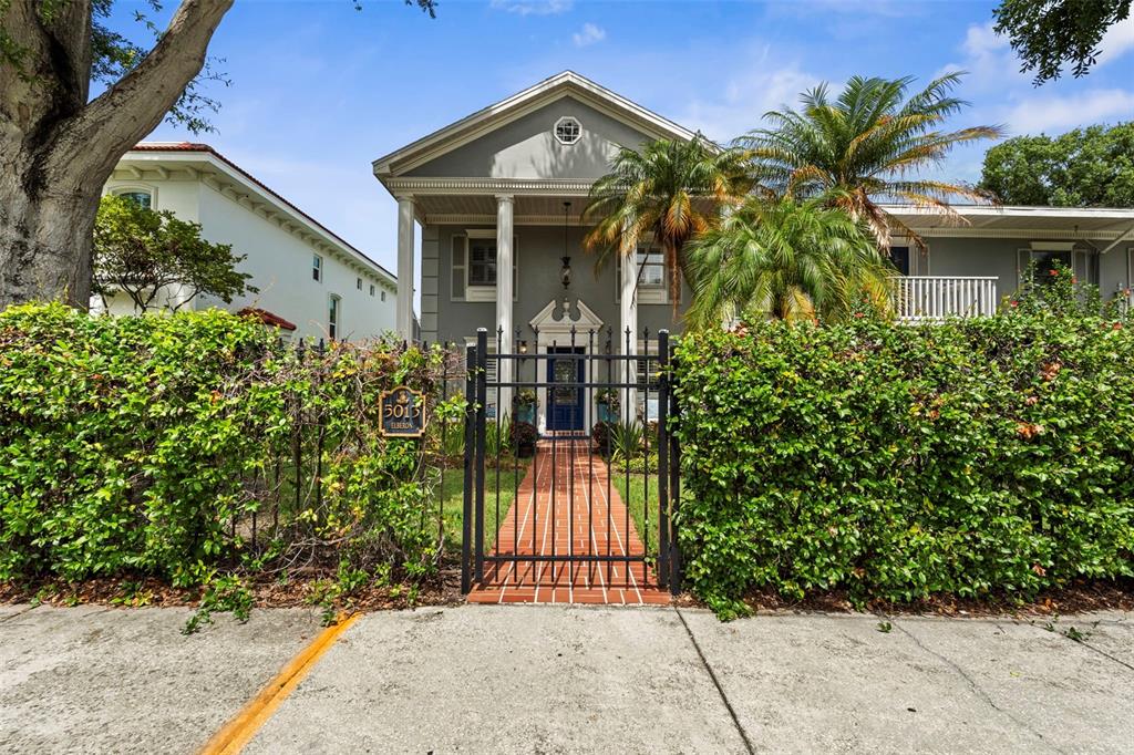 A two-story house with white columns and a brick walkway behind a black metal gate — 5013 S ELBERON STREET, TAMPA, FL