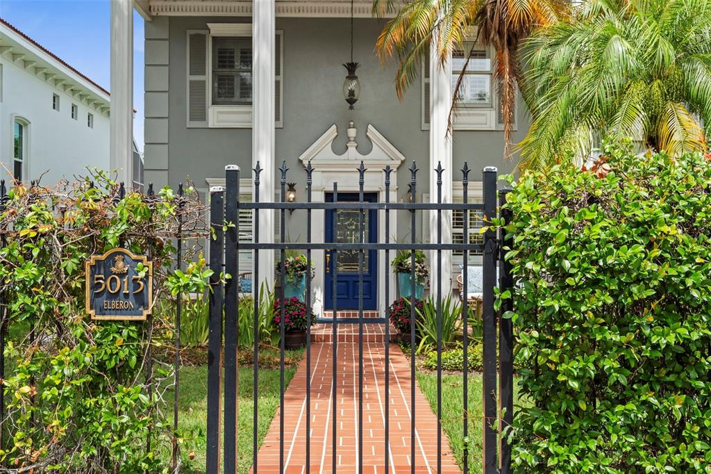 A gray two-story house features a brick walkway leading to a blue front door — 5013 S ELBERON STREET, TAMPA, FL