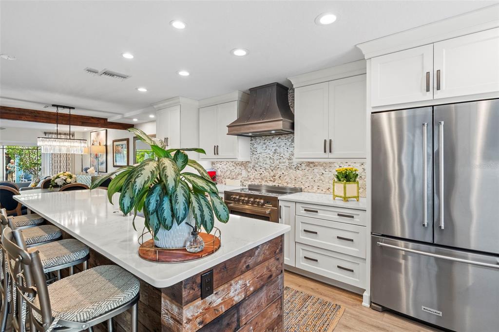 A kitchen features white cabinets, a rustic wood-paneled island, and stainless steel appliances — 5013 S ELBERON STREET, TAMPA, FL