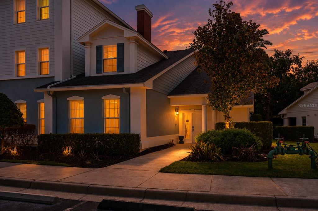 A two-story house with blue siding and a lit entryway at sunset — 7636 HERITAGE CROSSING WAY, REUNION, FL